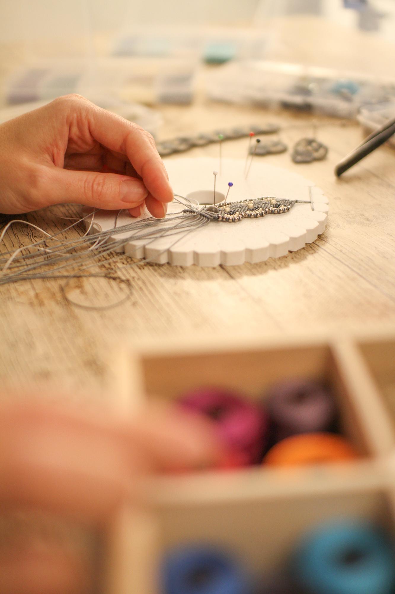 Workshop artisan stitching a pattern in neutral studio